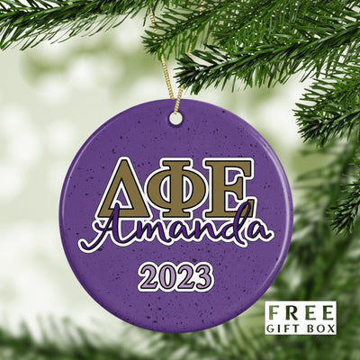 May include: Purple and gold Christmas ornament with the letters &#39;AΦE&#39; and the name &#39;Amanda&#39; in white lettering. The year &#39;2023&#39; is also on the ornament.