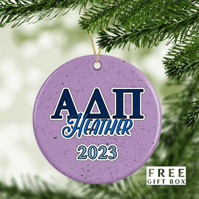 May include: Purple ceramic Christmas ornament with white speckles. The ornament has blue and white lettering that reads &#39;ΑΔΠ Heather 2023&#39;.