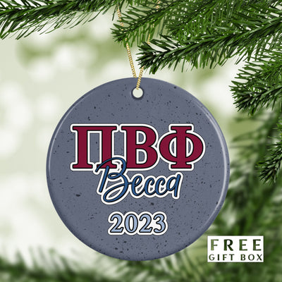 May include: A round, gray, ceramic ornament with a white speckled finish. The ornament features a red and blue Greek letter design, the word &#39;Becca&#39; in blue script, and the year &#39;2023&#39; in white.