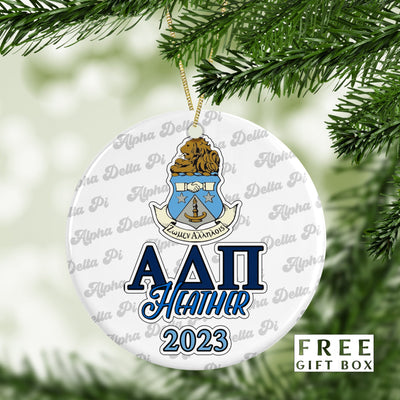 May include: A white round Christmas ornament with a blue and gold Alpha Delta Pi sorority crest and the text &#39;Alpha Delta Pi&#39;, &#39;Heather&#39;, and &#39;2023&#39;. The ornament is surrounded by a repeating pattern of the text &#39;Alpha Delta Pi&#39;.
