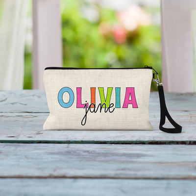 May include: A white canvas zippered pouch with a black zipper and a black strap. The pouch has the name &#39;OLIVIA jane&#39; printed on it in colorful letters.