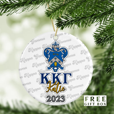 May include: A white round Christmas ornament with a blue and gold Kappa Kappa Gamma sorority crest. The ornament has the text &#39;KKГ Katie 2023&#39; printed on it. The ornament is surrounded by a white background with the text &#39;Gamma Kappa Gamma&#39; repeated in a gray font.